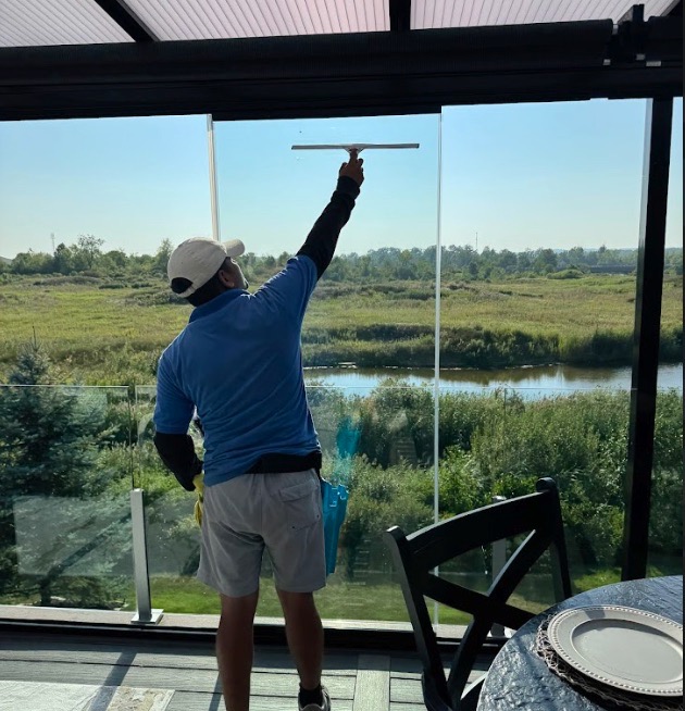 Technician cleaning large windows overlooking waterway