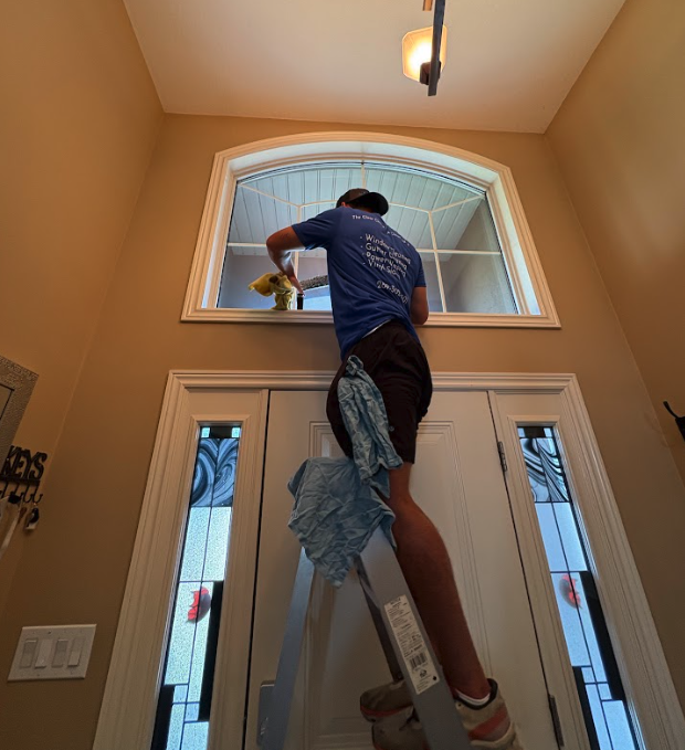 Technician on ladder cleaning interior window